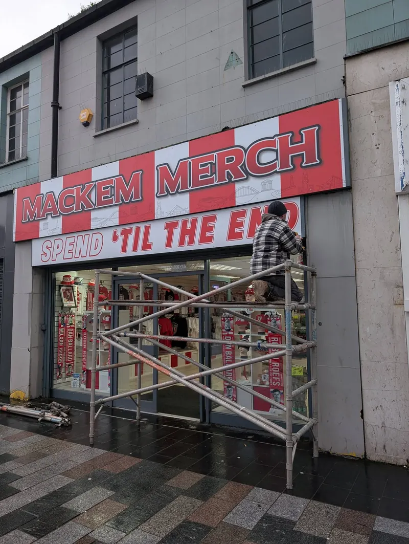 Mackem Merch fascia sign going up, with scaffolding in front of the shop