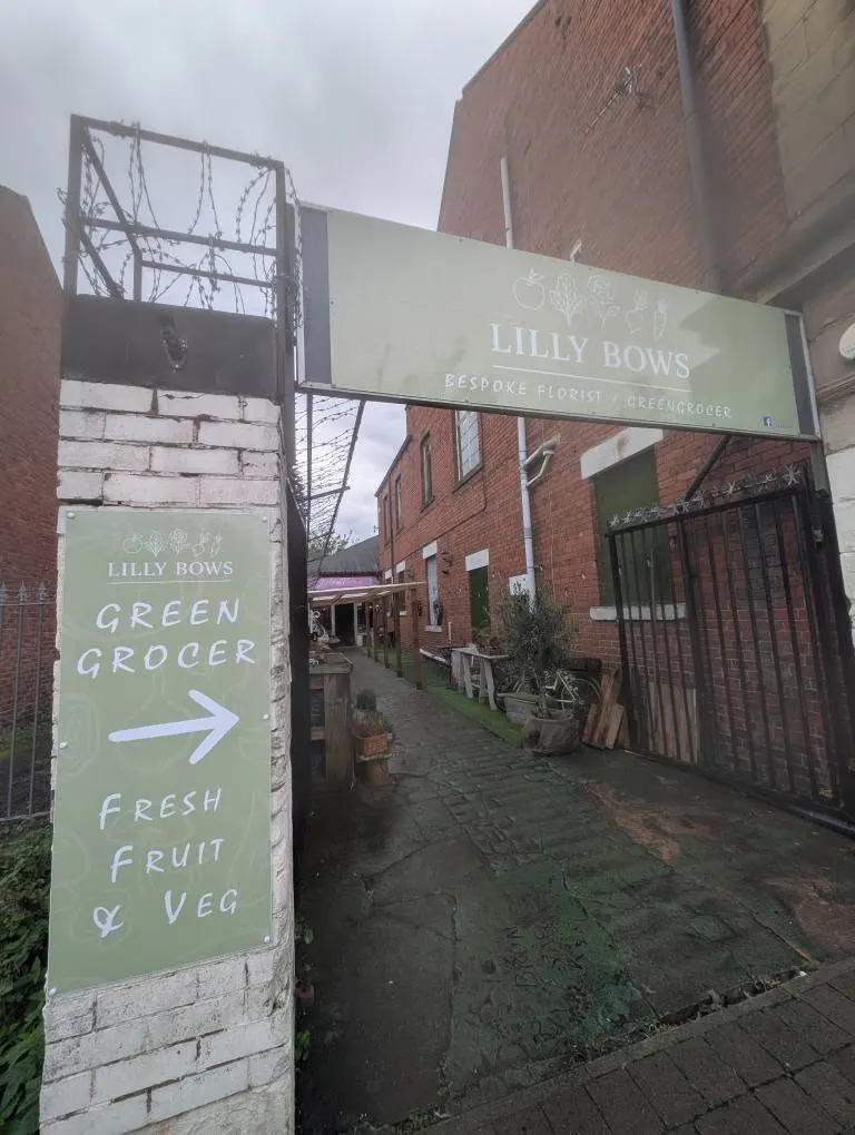 Sage green entrance sign and arrow sign for Lilly Bows florist and greengrocer