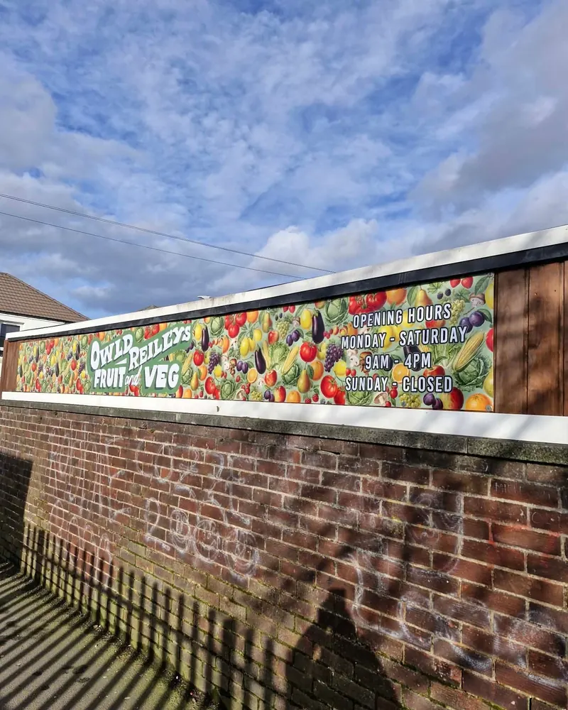 Printed banner along a brick wall for Owld Reilly's Fruit and Veg