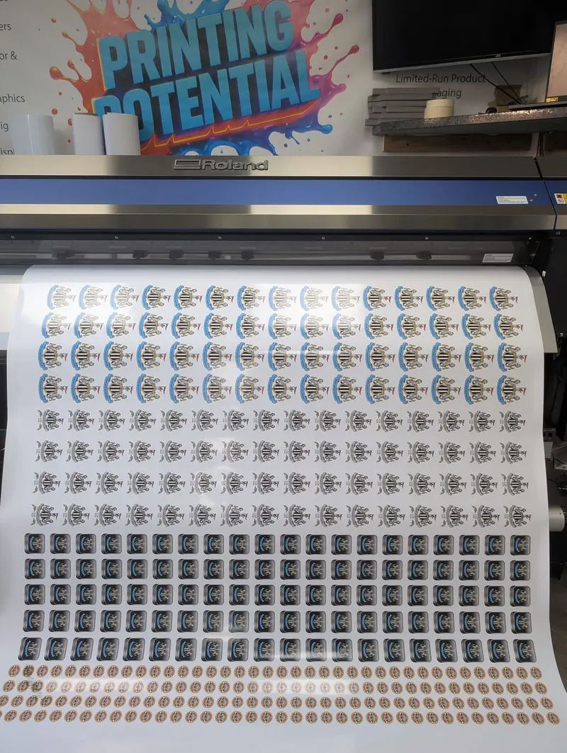 Sheet of printed, contour-cut stickers coming off the Roland printer/cutter